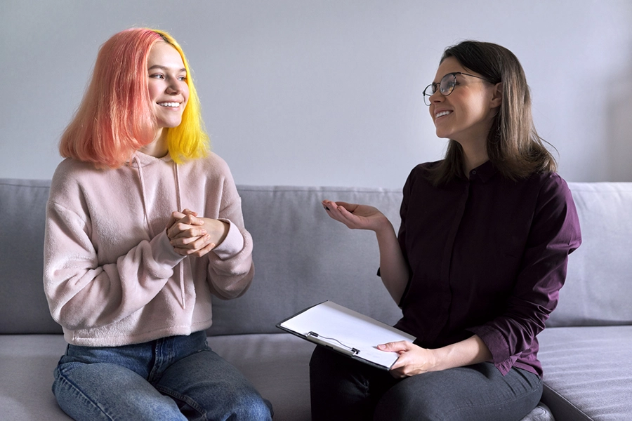  Teen girl giving interview to social worker. School psychologist talking with student, counseling, therapy, help and support for adolescents