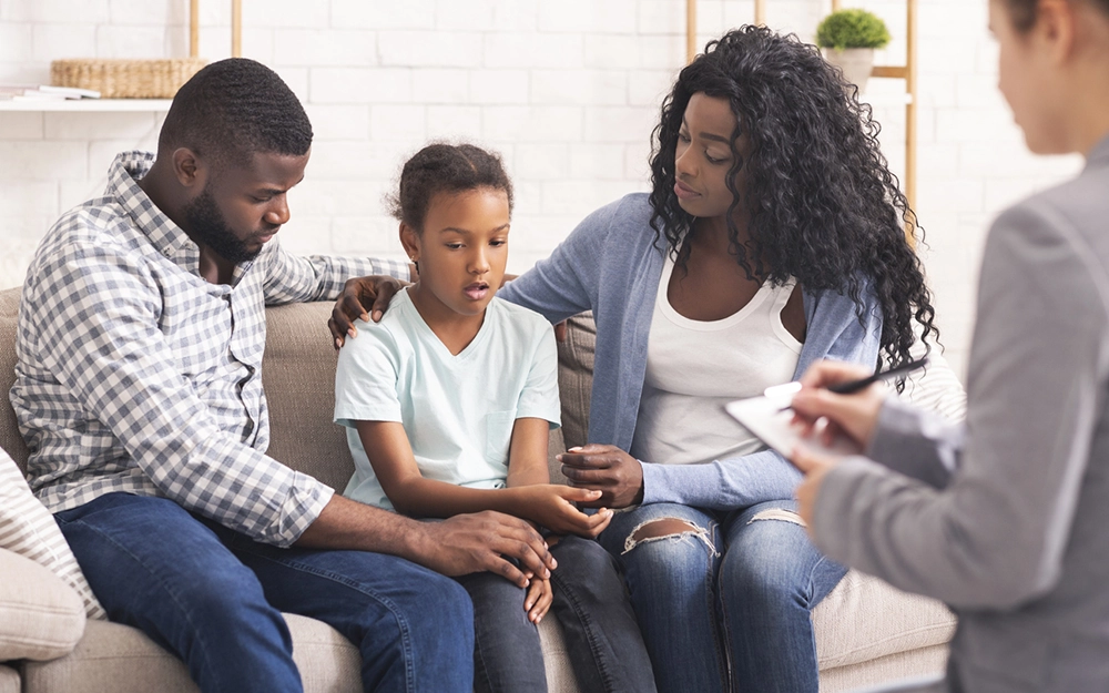 Child and family sitting on a couch in therapy