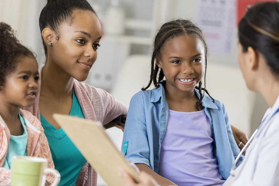 Confident cute African American girl talks with her doctor.