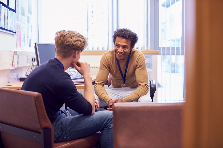 Male Student Meeting With Campus Counselor Discussing Mental Health Issues