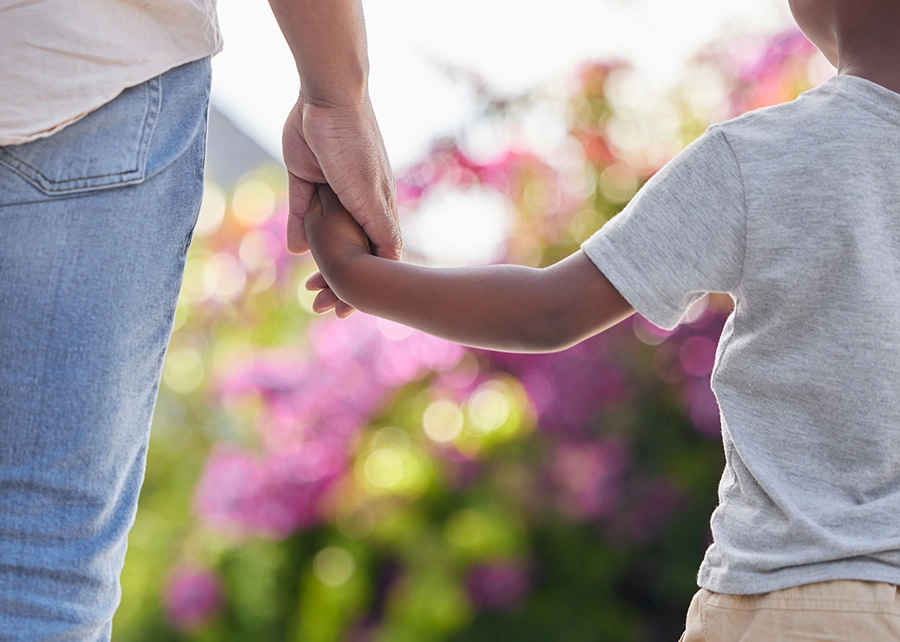 Closeup father and son holding hands while walking outside in the garden. A great role model and mentor for his boy child. A son will always look up to and follow in their dad's footsteps.