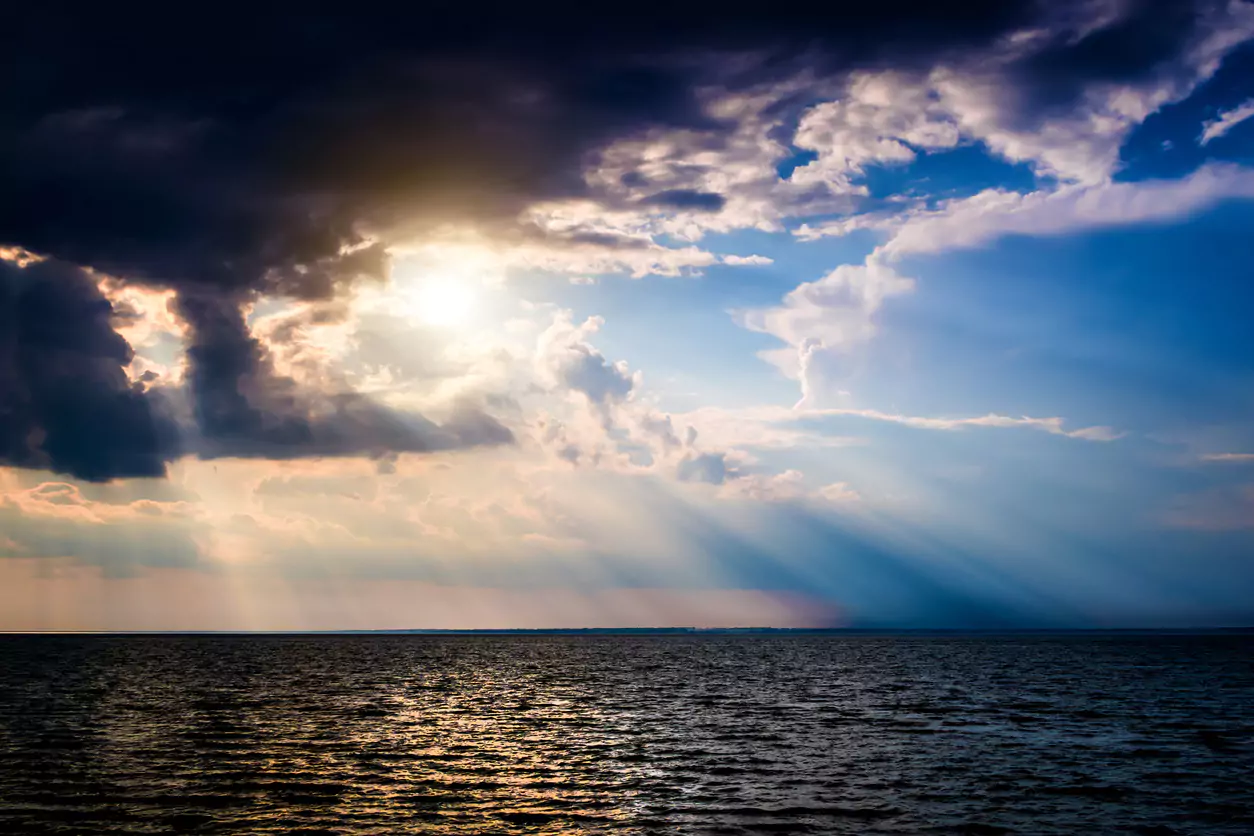 Rays of sunlight breaking through clouds over the ocean