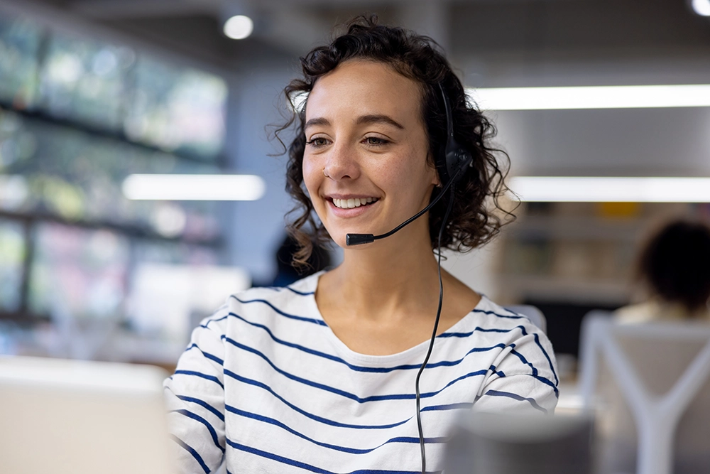 Happy Latin American customer service representative using a headset while working at a call center