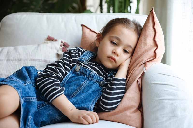 Sad little girl laying on the couch