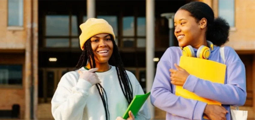 Two students standing together outside of a school