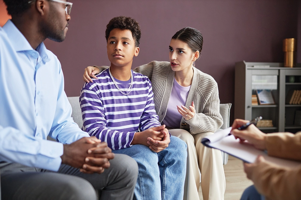 Parents arguing at a therapy session with their teenage son.