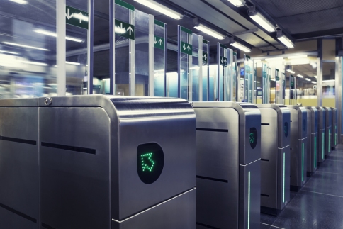 Stock image showing a row of subway entrance turnstiles, each one with green arrows lit up.